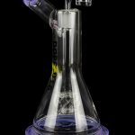 A clear glass water pipe (bong) with purple accents, featuring percolators and a mouthpiece, isolated on a black background.