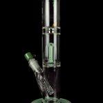 Green glass water pipe (bong) with intricate percolator design, isolated on a black background.