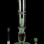 Green glass bubbler water pipe with detachable downstem and mouthpiece, reflecting on a dark surface.