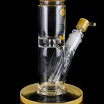 Glass water pipe (bong) with a gold-colored base and mouthpiece, isolated on a black background.