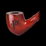 Red wooden pipe with carved symbol against a black background.