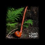 A wooden smoking pipe rests on moss and ferns, evoking a natural, earthy aesthetic, with "The Lord of the Rings" logo subtly displayed.