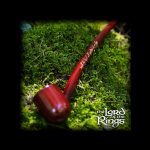 Red glass pipe resting on a bed of vibrant green moss, evoking a natural, earthy aesthetic.