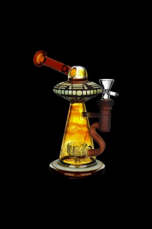 Ornate glass water pipe shaped like a UFO with amber and brown tones, isolated on a black background.
