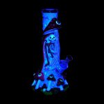 Glow-in-the-dark glass water pipe shaped like a skeleton wearing a witch hat, surrounded by glowing mushrooms.