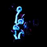 Glowing blue psilocybin mushrooms beside a cannabis pipe and grinder on a black background.
