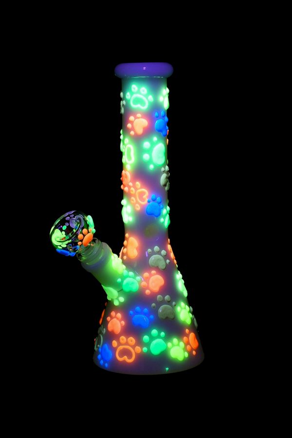 Glowing glass bong with colorful paw print design.