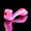 Pink glass pipe with a maple leaf design, reflected on a black surface.