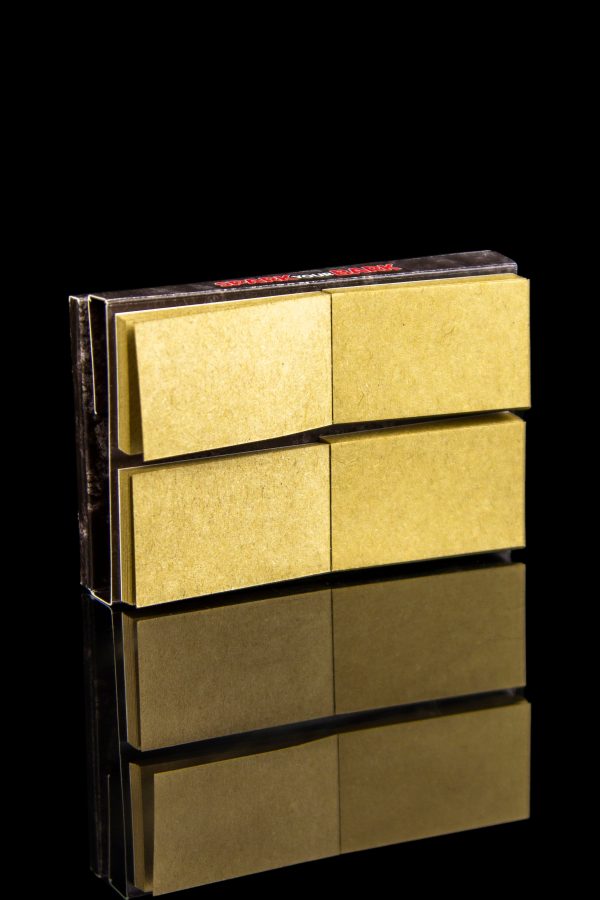Gold rolling paper booklets stacked with a mirrored reflection on a black background.