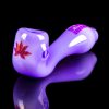 Purple glass pipe with cannabis leaf decal, reflected on a black surface.