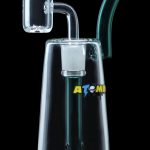 Clear glass dab rig with a quartz banger and colorful accents, branded “ATOMI”.