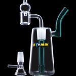 Clear glass rig with percolator and detachable mouthpiece, alongside a glass bowl, on a dark surface.