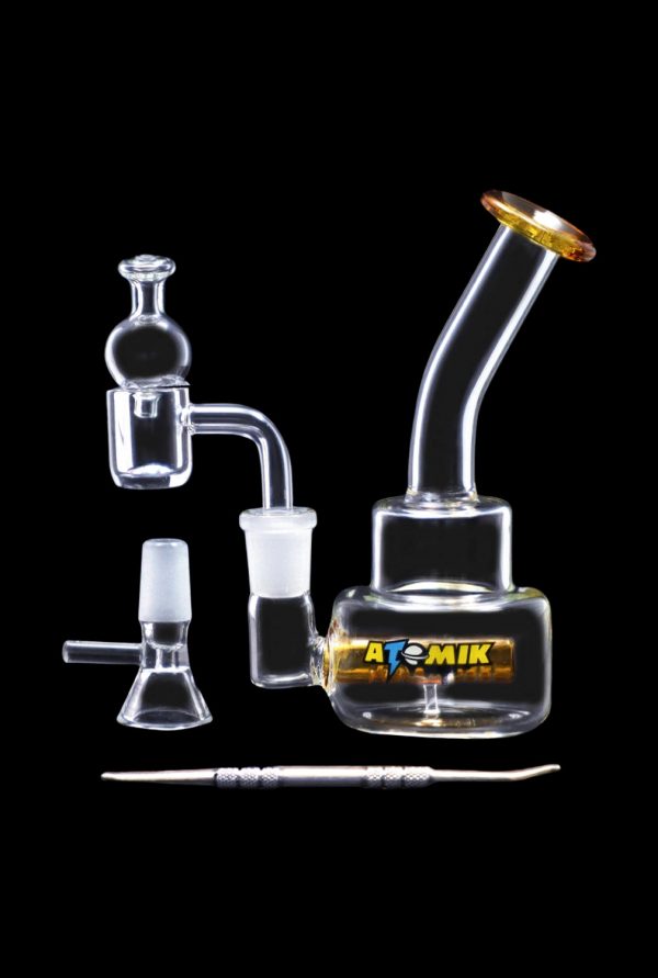 Glass dab rig and accessories on black background.