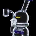 Clear glass dab rig with blue accents and a quartz nail.