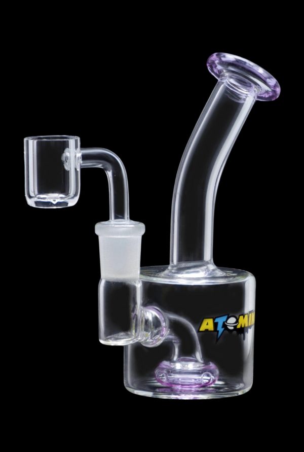 A studio shot of the Atomik Little Dipper Dab Rig, showcasing its compact size and clear glass construction from a three-quarter angle.