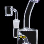 The Atomik Little Dipper Dab Rig appears in a studio shot, highlighting its clear glass construction and compact 5.25-inch size.