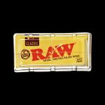 The RAW Classic Pack Glass Ashtray is shown in a close-up, angled view with visible branding on a black background.