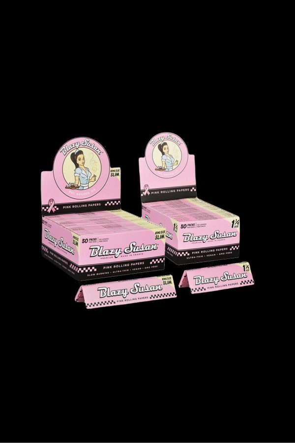 Stacked packs of pink “Blazy Susan” rolling papers with a checkerboard pattern, displayed on a black background.