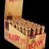 A stack of RAW Natural 1 ¼" Unrefined Pre Rolled Cones is displayed against a dark backdrop, showcasing the branded packaging.