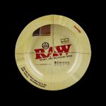 Overhead view of the RAW Round Metal Magnetic Ashtray, featuring circular branding and a textured, metallic surface.