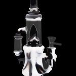 Black and white glass water pipe (rig) with intricate dripping design.