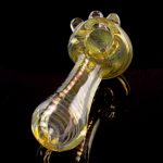 A detailed side view of the Gold Fumed Spoon Pipe - Midas, showcasing its curved shape and golden sheen against a black background.