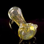 A side view of the Gold Fumed Spoon Pipe - Midas, featuring gold accents and a curved bowl against a dark backdrop.