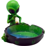 A detailed view of the Smoking Alien Ashtray, showing a green alien figurine holding a cigarette over a small, dark-colored ashtray.