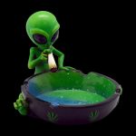 A close-up of the Smoking Alien Ashtray, showing a green alien figure holding a dish, captured with dramatic lighting.
