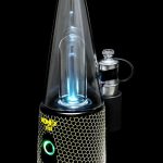 A lit, portable dab rig with a honeycomb-textured base and glowing blue interior, accompanied by a metal carb cap.
