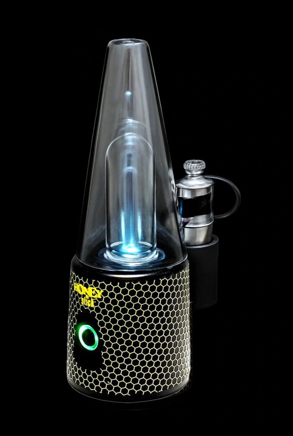 A lit, portable dab rig with a honeycomb-textured base and glowing blue interior, accompanied by a metal carb cap.