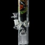 A glass bong with a green base and colorful, illustrative artwork depicting skulls and floral designs.