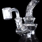 Clear glass dab rig with intricate bubbler design and quartz banger.