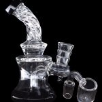 Clear glass water pipe (rig) with attachments against a black background.
