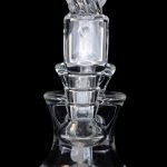 Clear glass dab rig with intricate sculpting and rounded base, isolated on a black background.