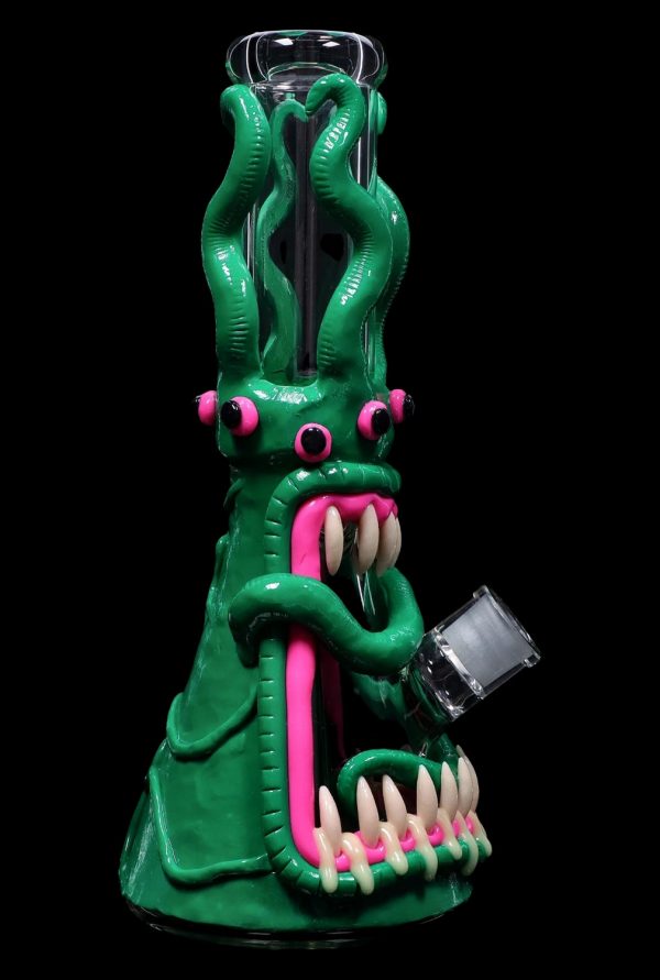 Green glass monster-themed water pipe with pink accents, displayed against a black background.