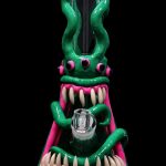 Green glass water pipe shaped like a monster with sharp, white teeth and pink accents, featuring a glass bowl.