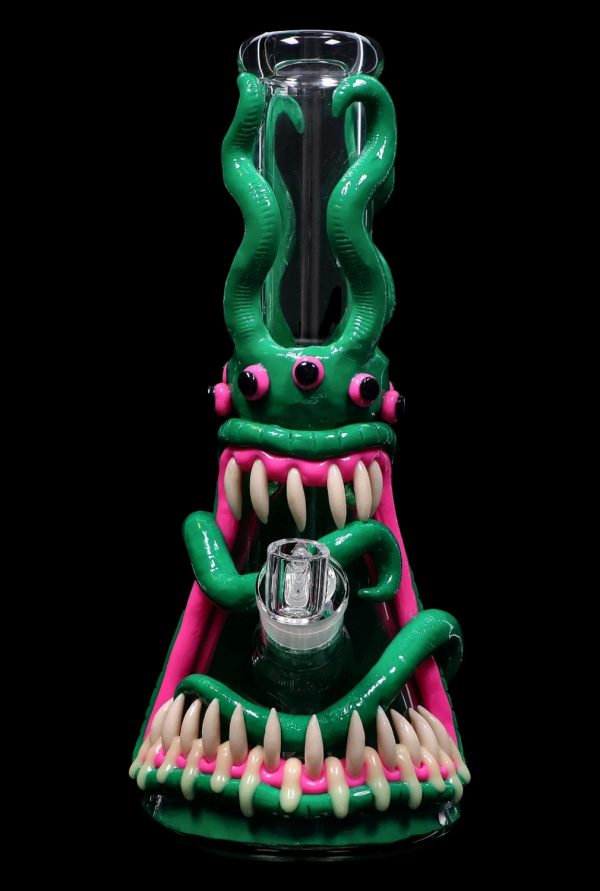 Green glass water pipe shaped like a monster with sharp, white teeth and pink accents, featuring a glass bowl.