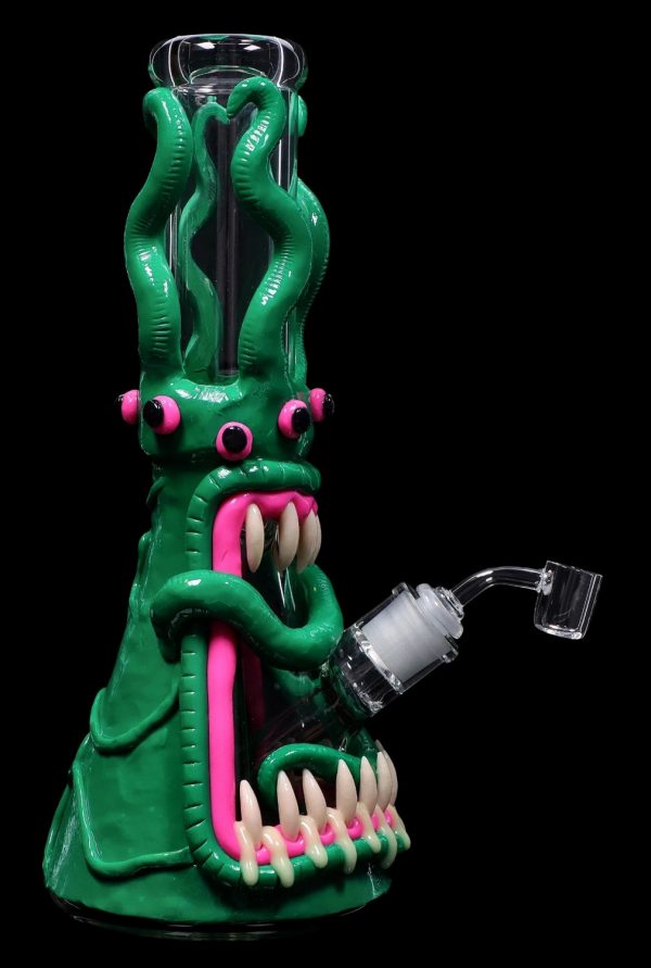 A vibrant green glass rig shaped like a monster with a wide-open mouth, pink tongue, and multiple tentacles, featuring a quartz banger for dabbing cannabis concentrates.