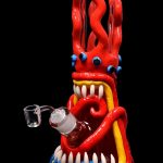 Red glass bong shaped like a monster with large teeth and googly eyes.