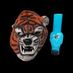 A vibrant orange tiger mask and a blue glass water pipe stand against a black background.