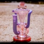 Pink and purple glass water pipe with intricate bubbler design.