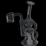 Clear glass dab rig with black accents and a quartz nail, isolated on a black background.