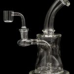 Clear glass dab rig with quartz banger, against a black background.