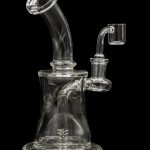 Clear glass dab rig with a bent neck and quartz banger, isolated on a black background.