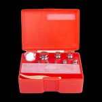 Red calibration weights in a plastic case, used for precision scales often associated with cannabis measurement.