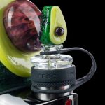 A close-up shot of the Empire Glassworks Avocadope Carb Cap for Puffco Peak, displaying a green, avocado-shaped design against a dark backdrop.