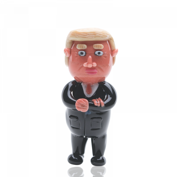 Front view of the Empire Glassworks “Agent Orange” Trump hand pipe, a sculpted, orange-toned figurine presented on a plain white background.