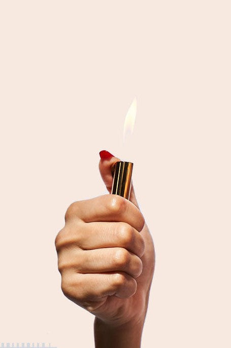 Hand holding a lit gold lighter, flame visible.