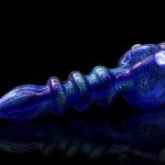 Blue glass cannabis pipe with textured surface and reflective sheen, displayed against a black background.